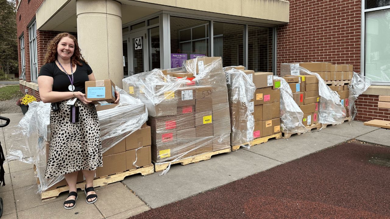 Carmen Grace Poppert posing next to the 140 boxes that contained Risen Christ’s new curriculum.